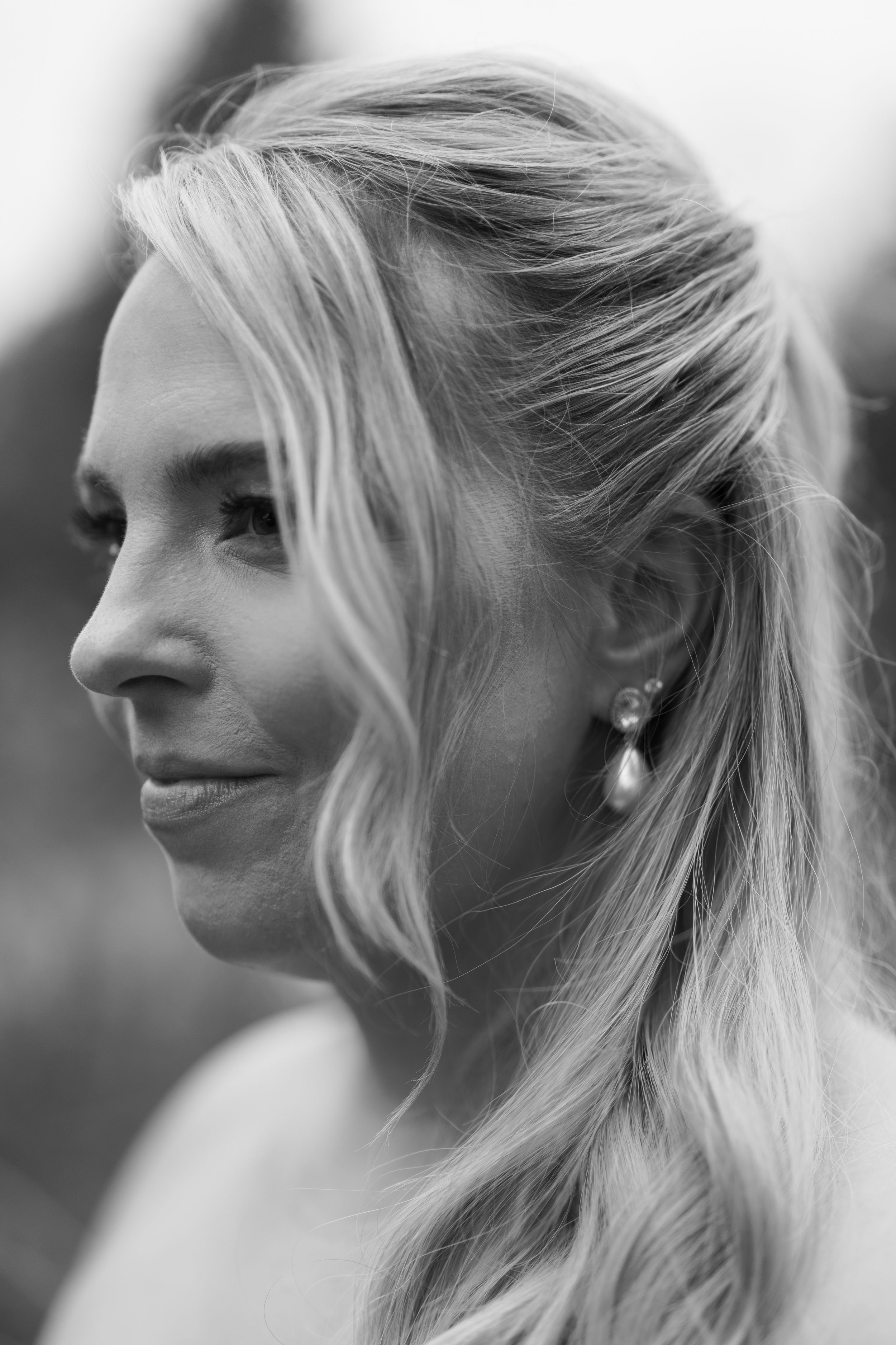 Black and white profile portrait of a blonde woman wearing pearl drop earrings, with hair swept back elegantly.