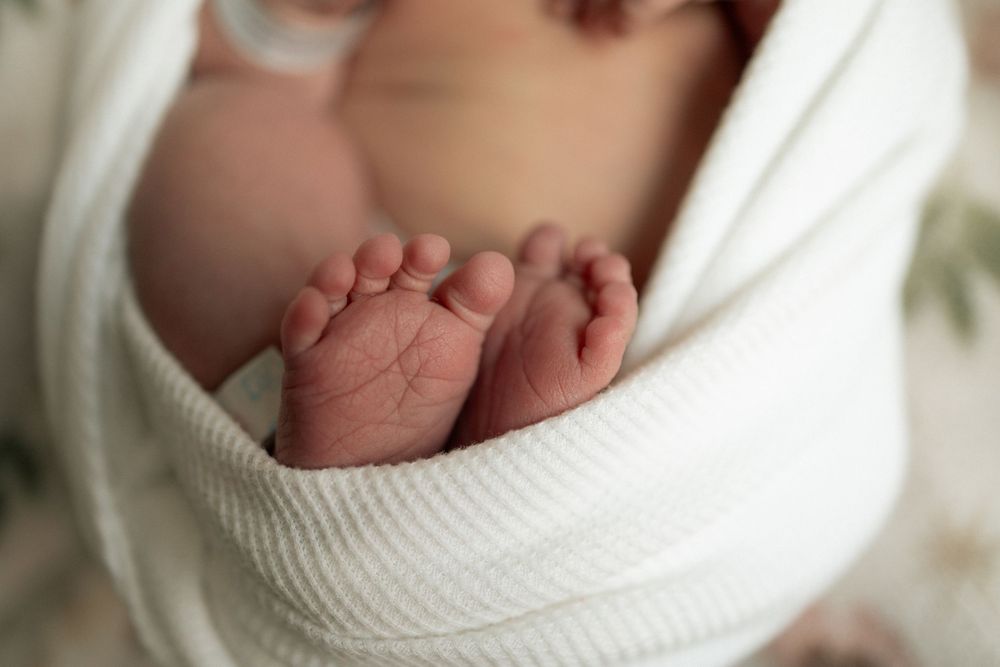 Close-up of newborn baby feet wrapped in a soft white swaddle blanket, perfect newborn photography.