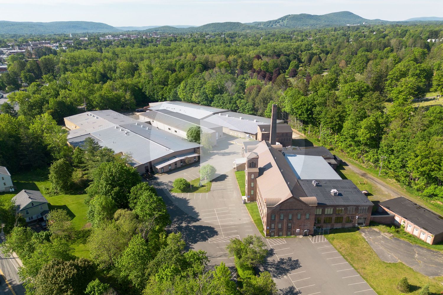 Aerial view of sprawling industrial buildings nestled among dense green trees and hills.