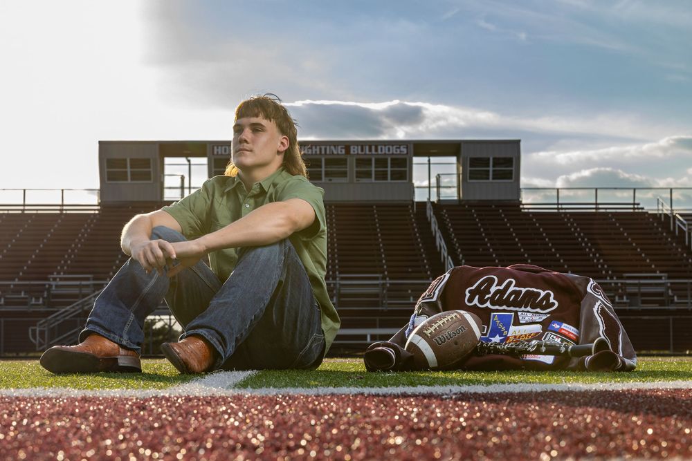 senior pictures on the football field with letterman jacket, football and clarinet