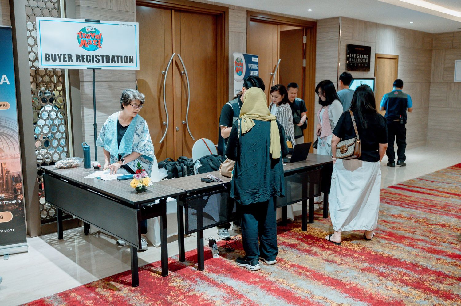 People registering at a buyer registration desk in a hotel conference room during a business event.