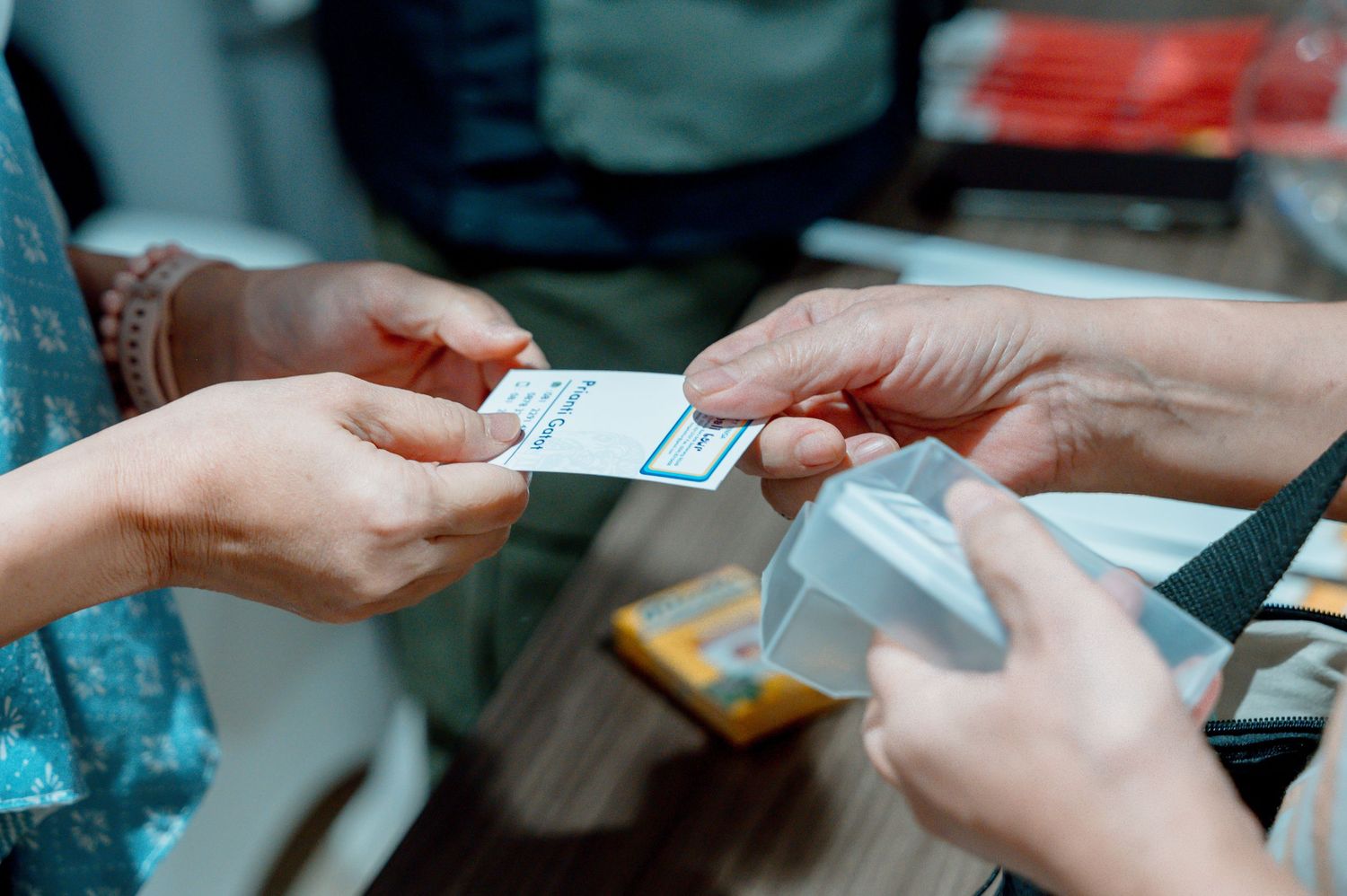 Close-up of two people exchanging a small card or ticket at a registration desk during an event.
