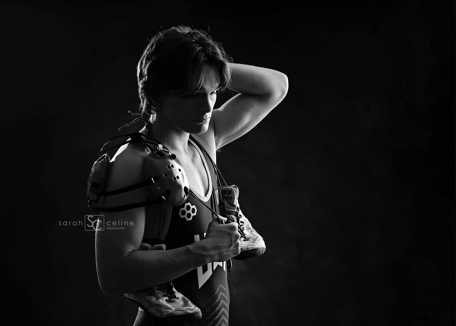 Black and white photo of a woman in warrior armor holding a sword, posing dramatically against a dark background.