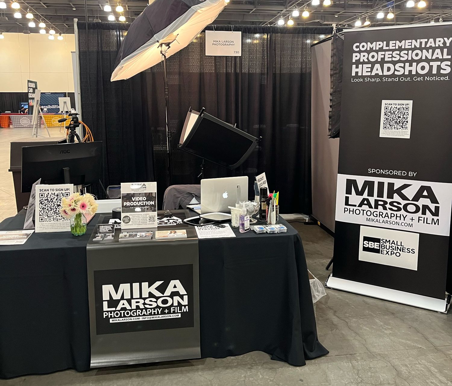 Mika Larson Photography and Film trade show booth offering complimentary professional headshots at a business expo.