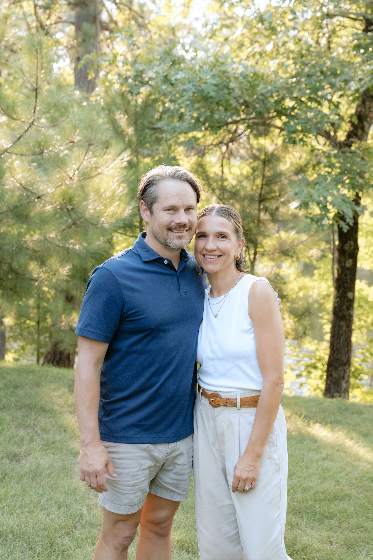 Parents hug and smile at the camera during an outdoor family session in Holcombe, WI.