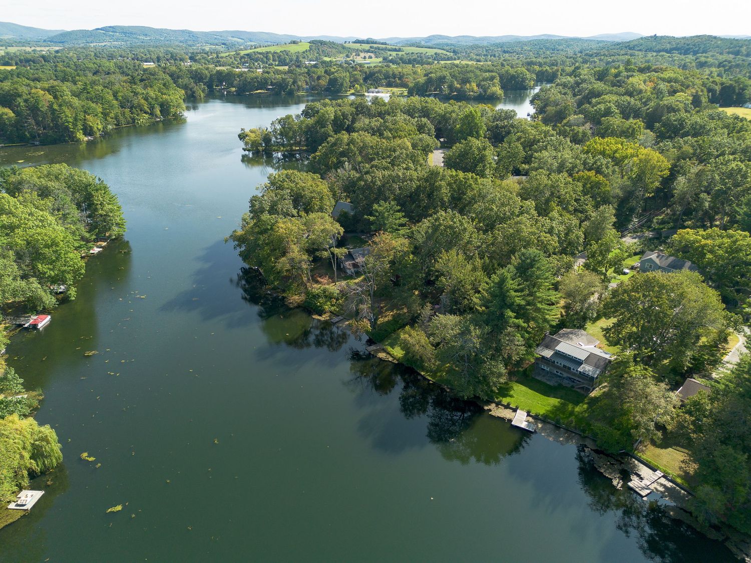 Aerial view of winding river bordered by lush trees and waterfront homes.