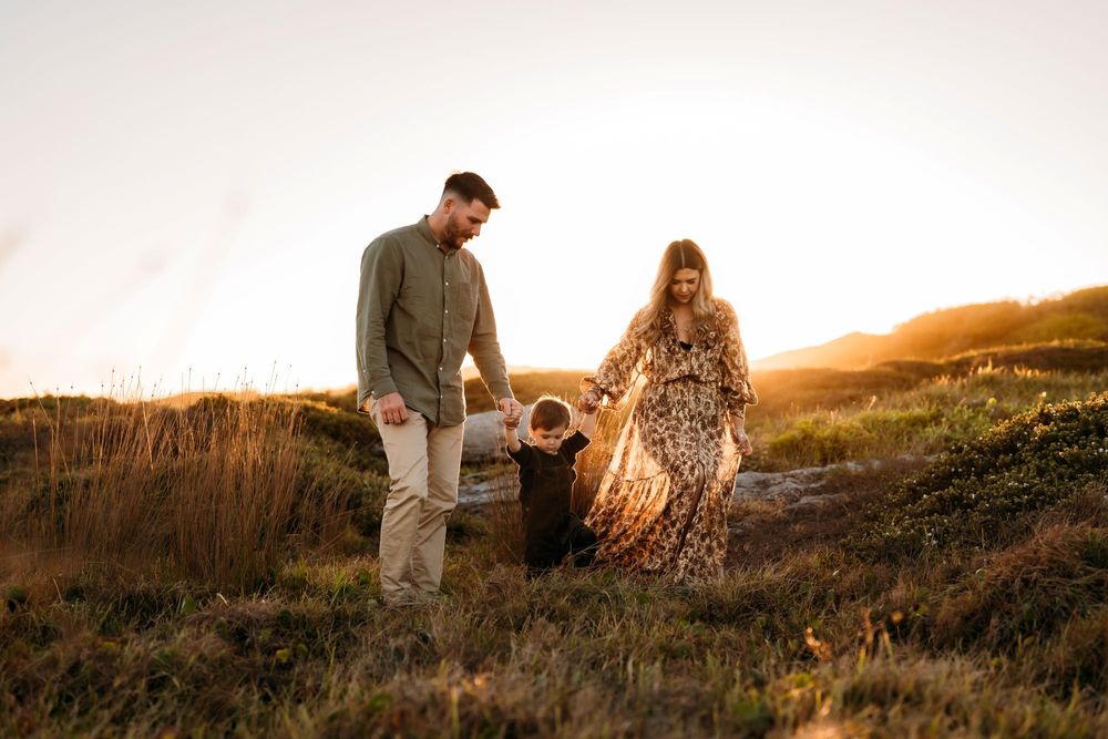 Family walking together on a grassy hillside during golden hour sunset in Sydney