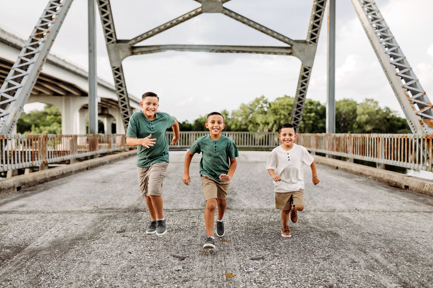 Three children running together across a metal bridge structure.