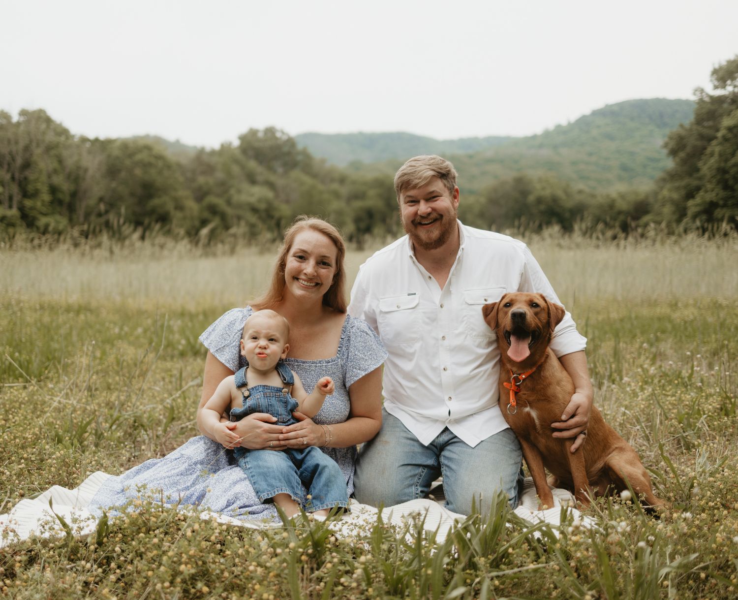 A family portrait in a golden autumn field with casual attire and natural lighting.