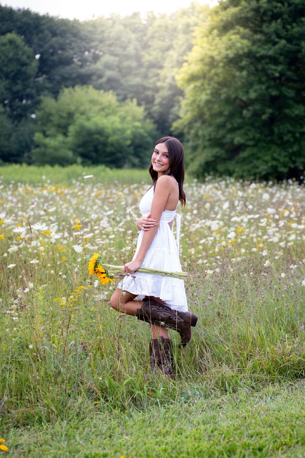 Natural light portrait session in a field with sunflowers and vintage accessories.