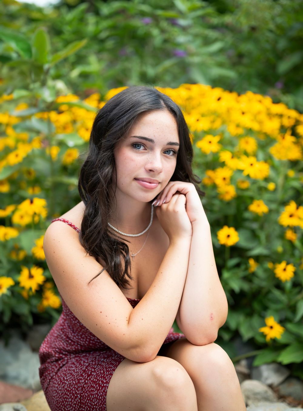 Portrait session among vibrant yellow flowers with burgundy dress details.