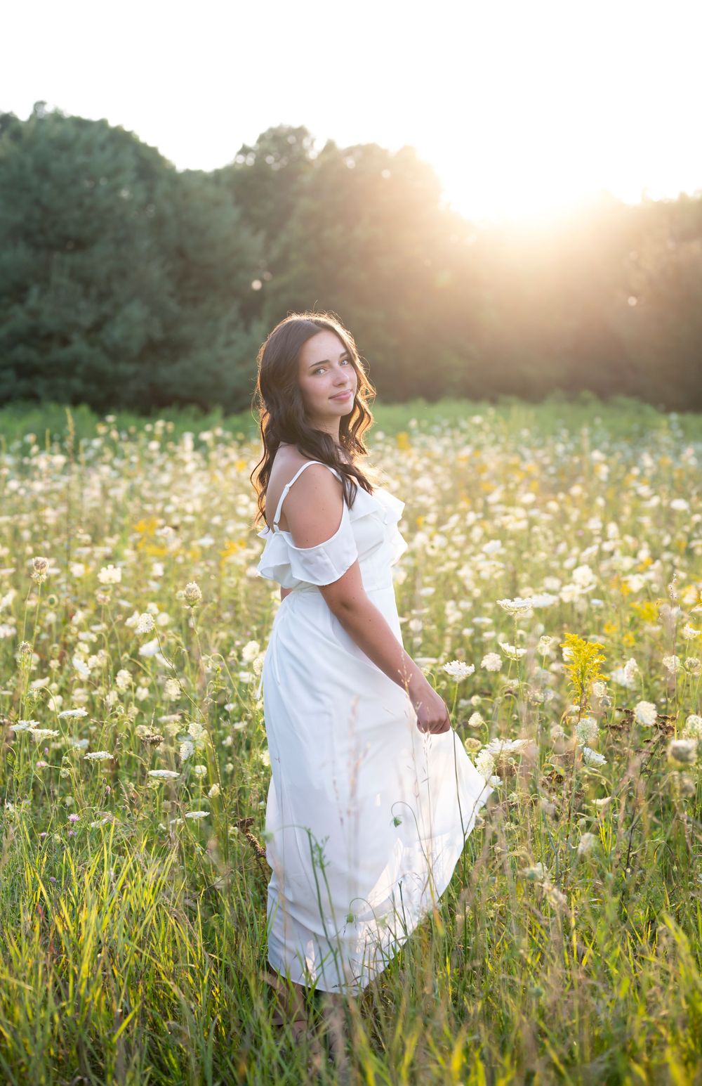 Ethereal white dress portrait session in a sunlit wildflower meadow.