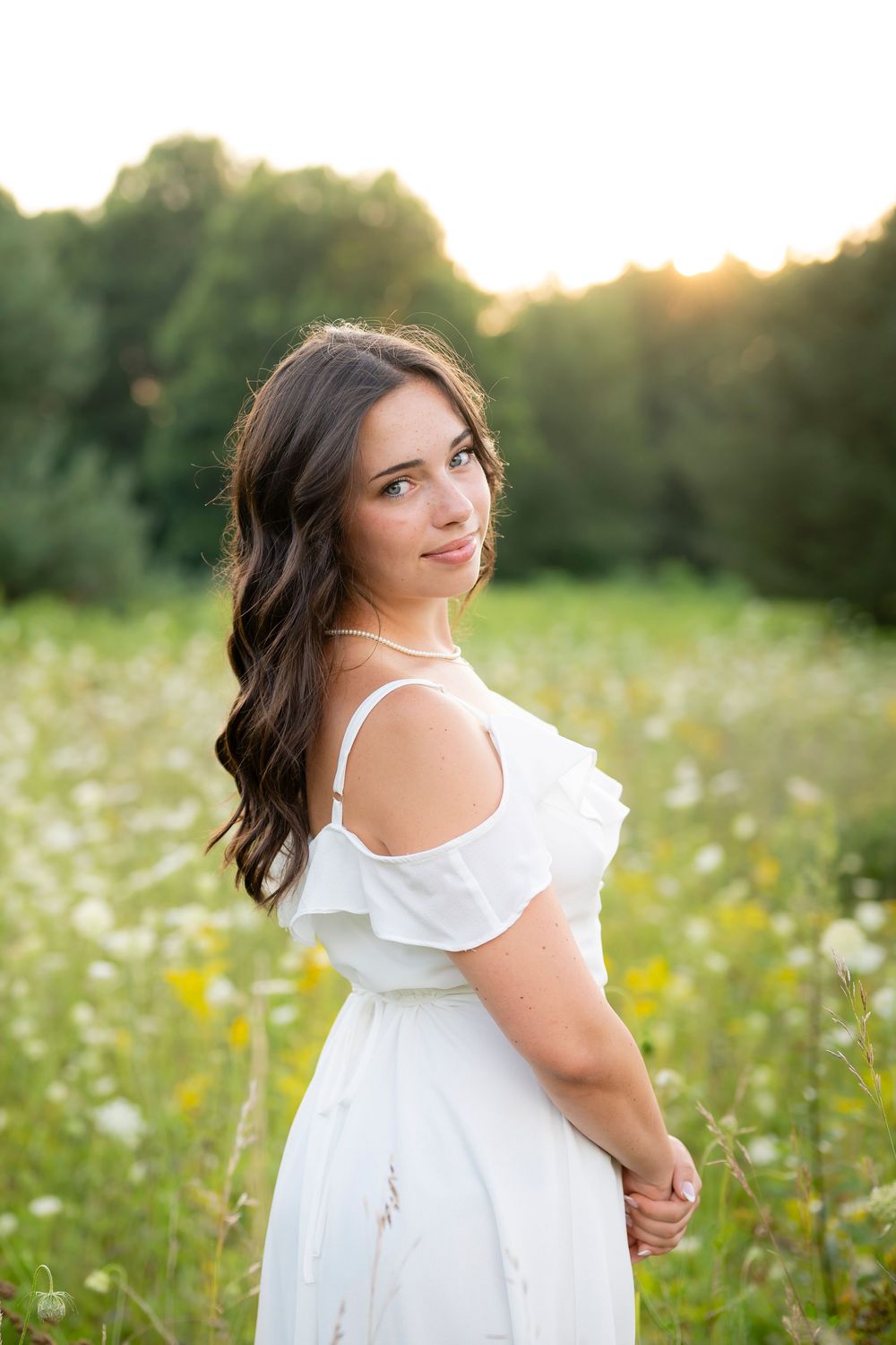 Romantic white dress portraits in a summer meadow at golden hour.