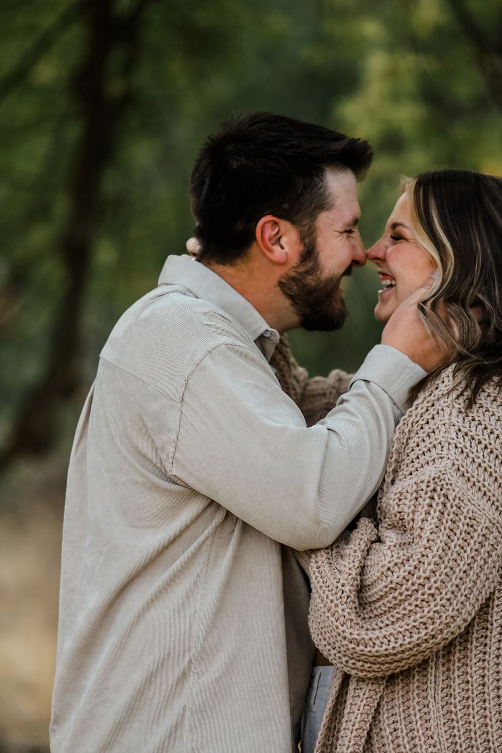 A romantic couple in cozy sweaters sharing intimate moments against a natural outdoor backdrop.