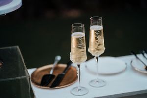 Elegant champagne flutes filled with bubbly wine sit on a white surface against a dark background.