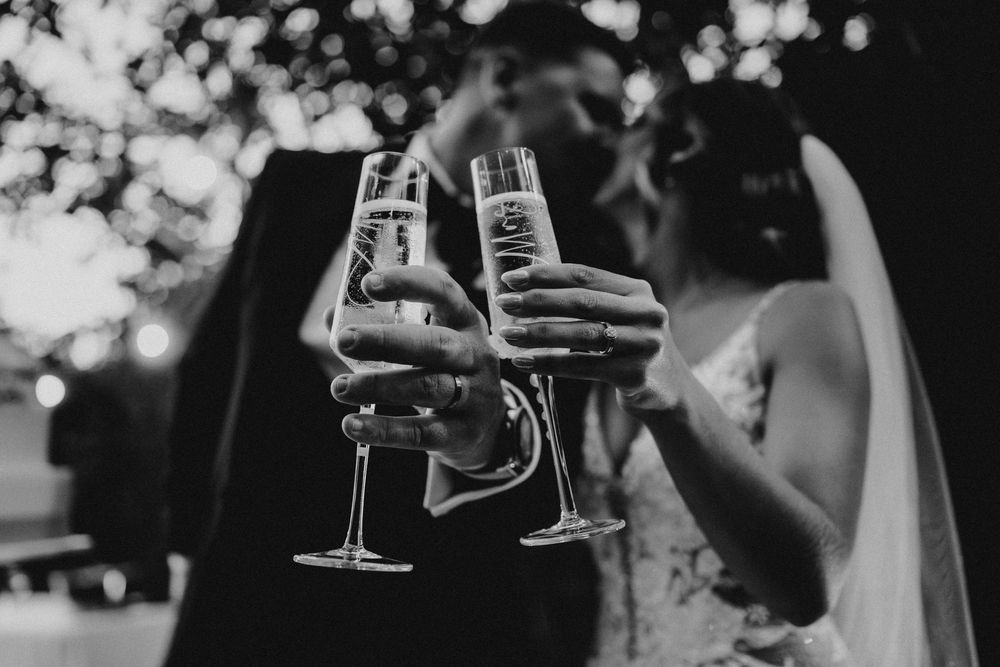 People holding wine glasses in a celebratory toast at an outdoor event with bokeh lights in the background.
