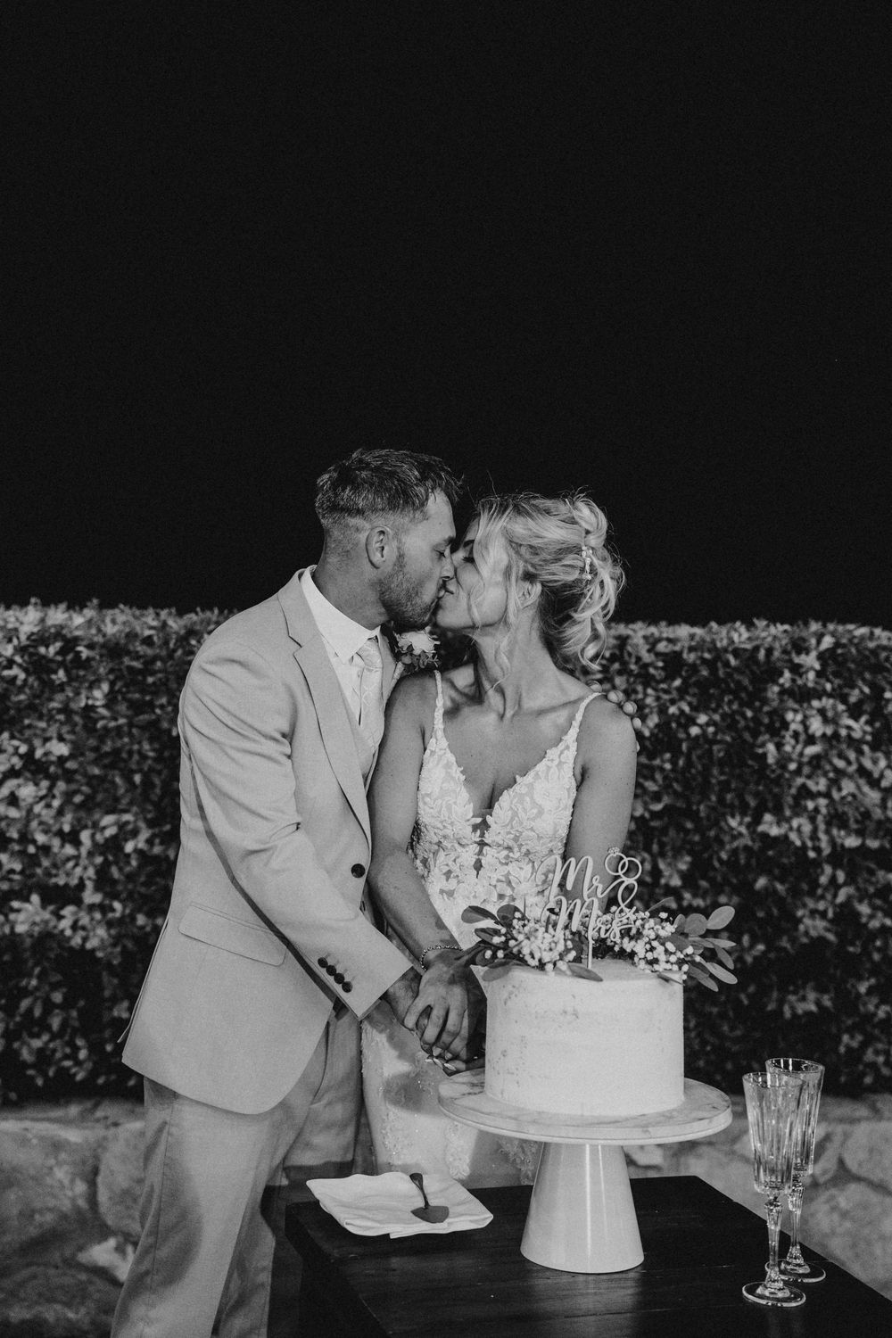 Black and white wedding photo sequence showing couple sharing a sweet moment while cutting their tiered cake together.
