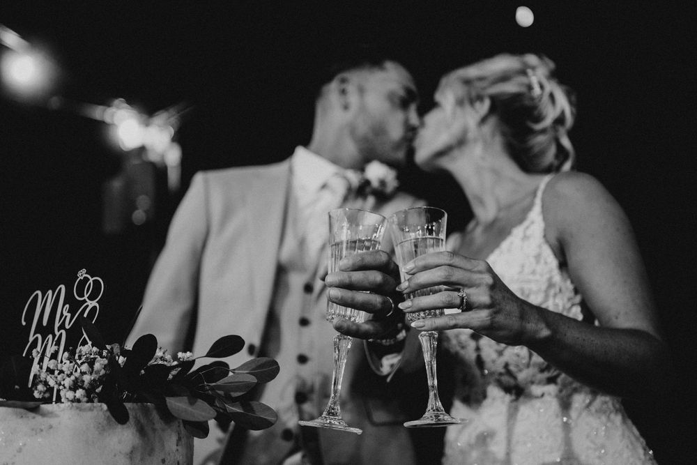 A black and white photo of wedding reception guests toasting with champagne glasses at an elegant celebration.