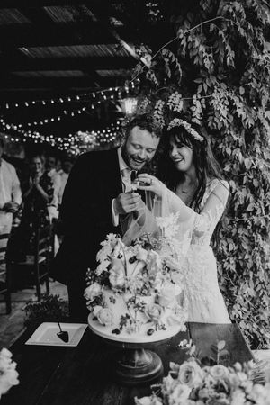 A couple shares intimate moments during their wedding reception under twinkling string lights and greenery.