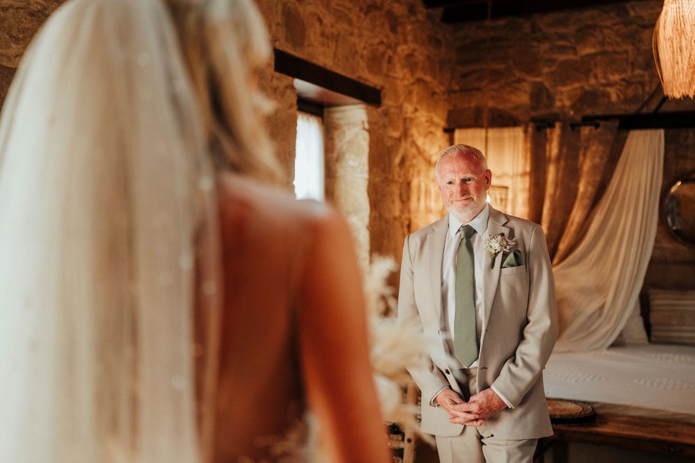 A bride and groom share an intimate moment during their wedding ceremony in a rustic wooden setting.