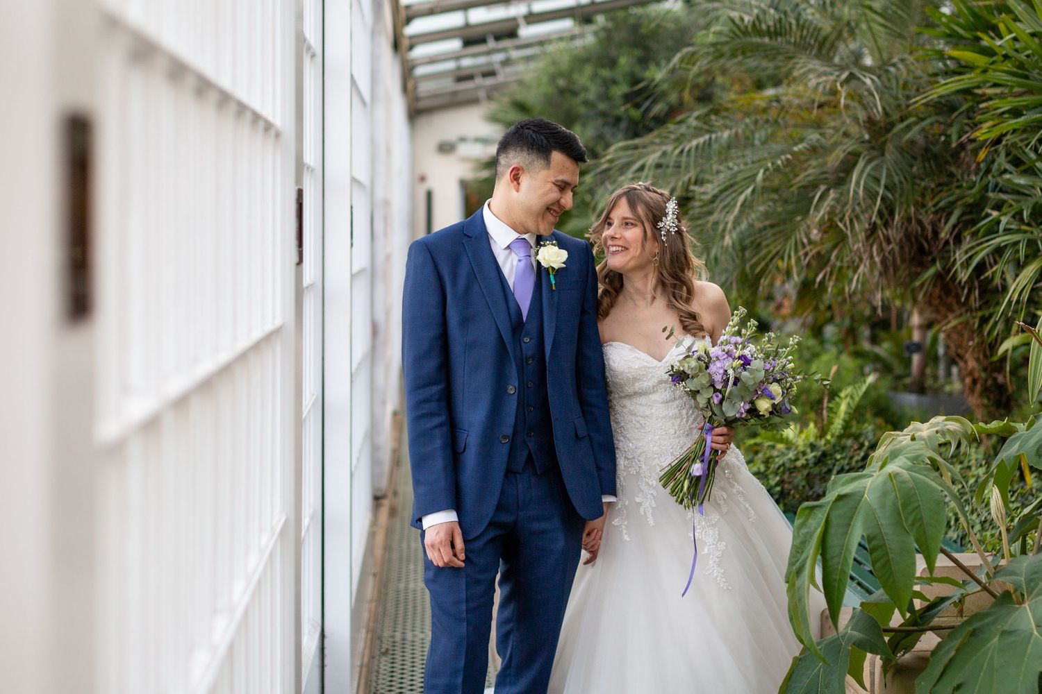 A wedding couple shares an intimate moment against a backdrop of lush greenery.