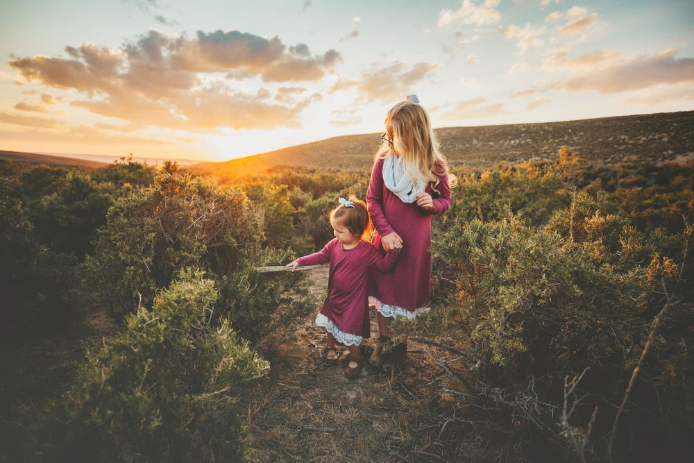 Two little girls walk through brush and grass at sunset in Dickson, TN