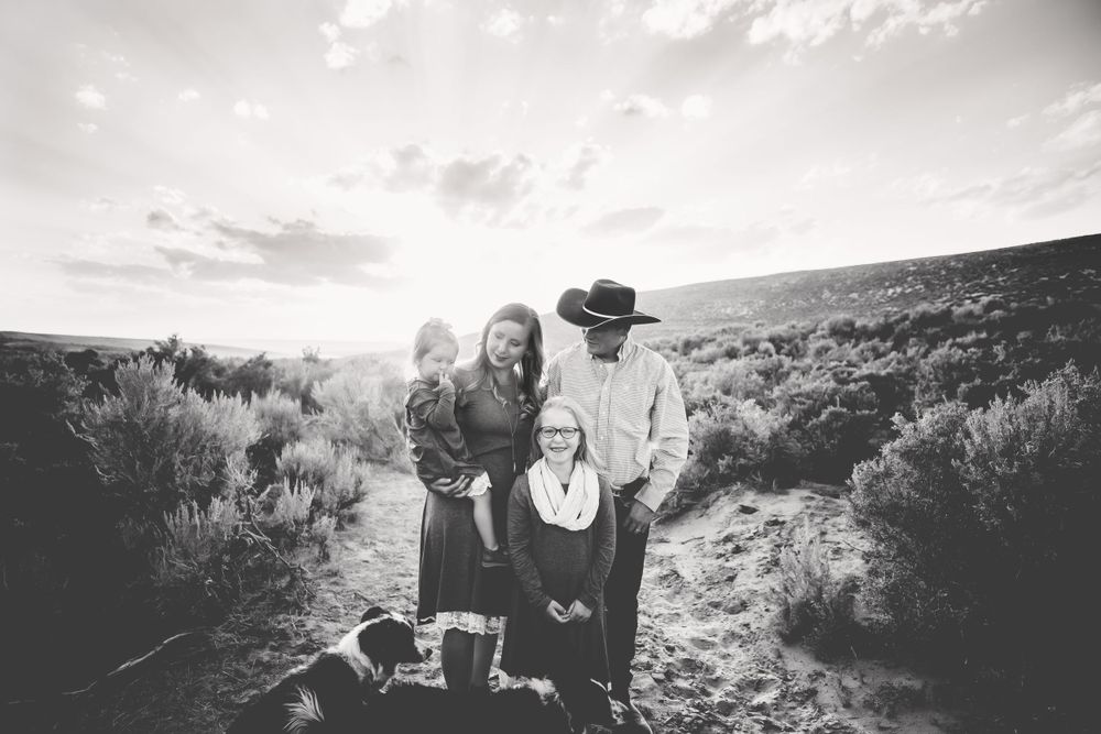 Mom, Dad, two daughers, and two dogs stand and smile in black and white at sunset in Dickson, TN
