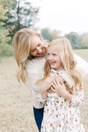 A joyful moment shared between parent and child laughing together outdoors in autumn light.