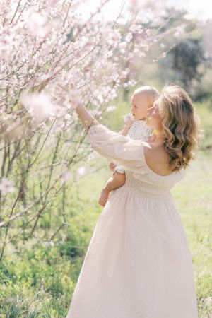 Two figures standing by blooming cherry blossom trees in a spring garden with soft sunlight filtering through branches.