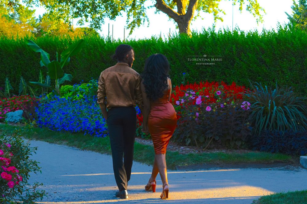 A couple walking hand in hand through a garden path with colorful flowers at sunset.