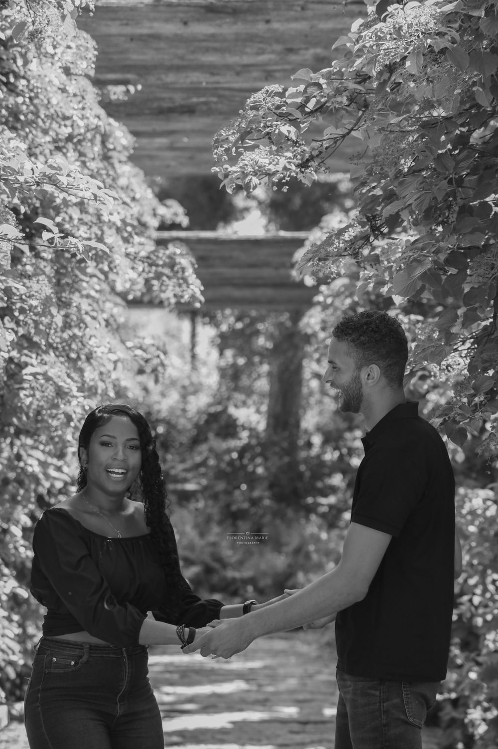 Black and white portrait in a garden archway framed by flowering branches.