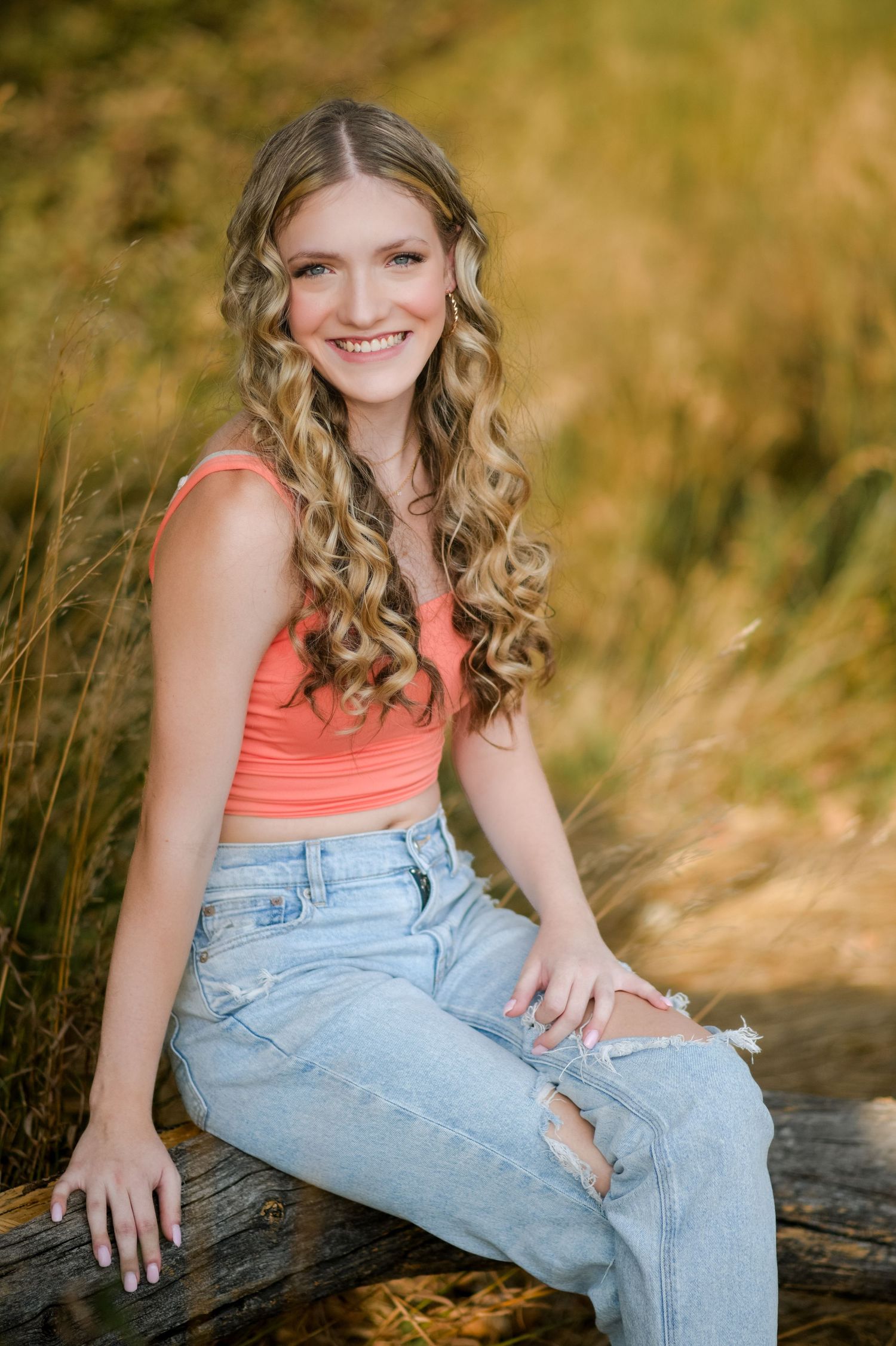 A series of outdoor portrait photos showing someone in a coral tank top and light denim jeans posing on a log.