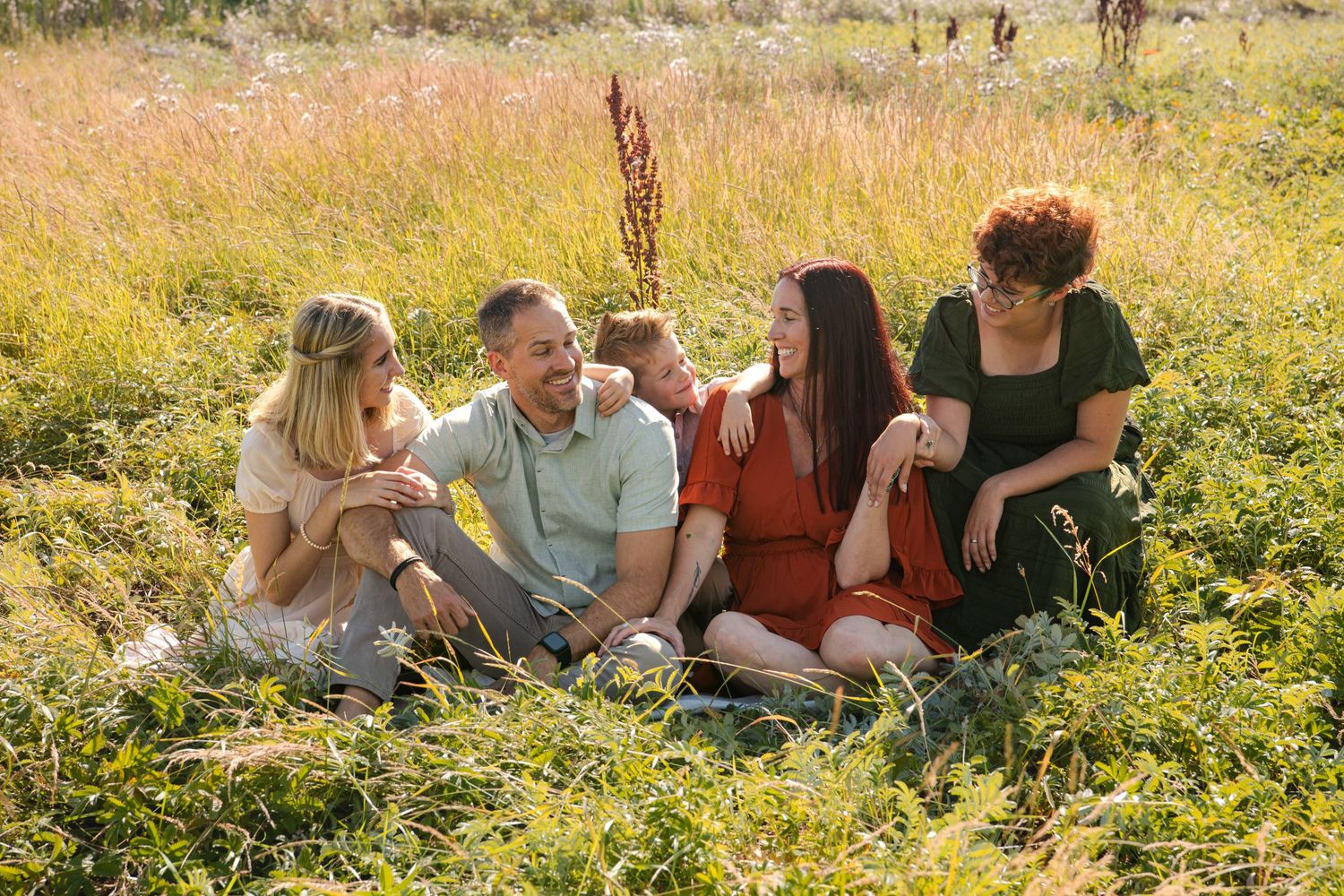 A group sits together in a sunny meadow filled with wildflowers on a warm summer afternoon.