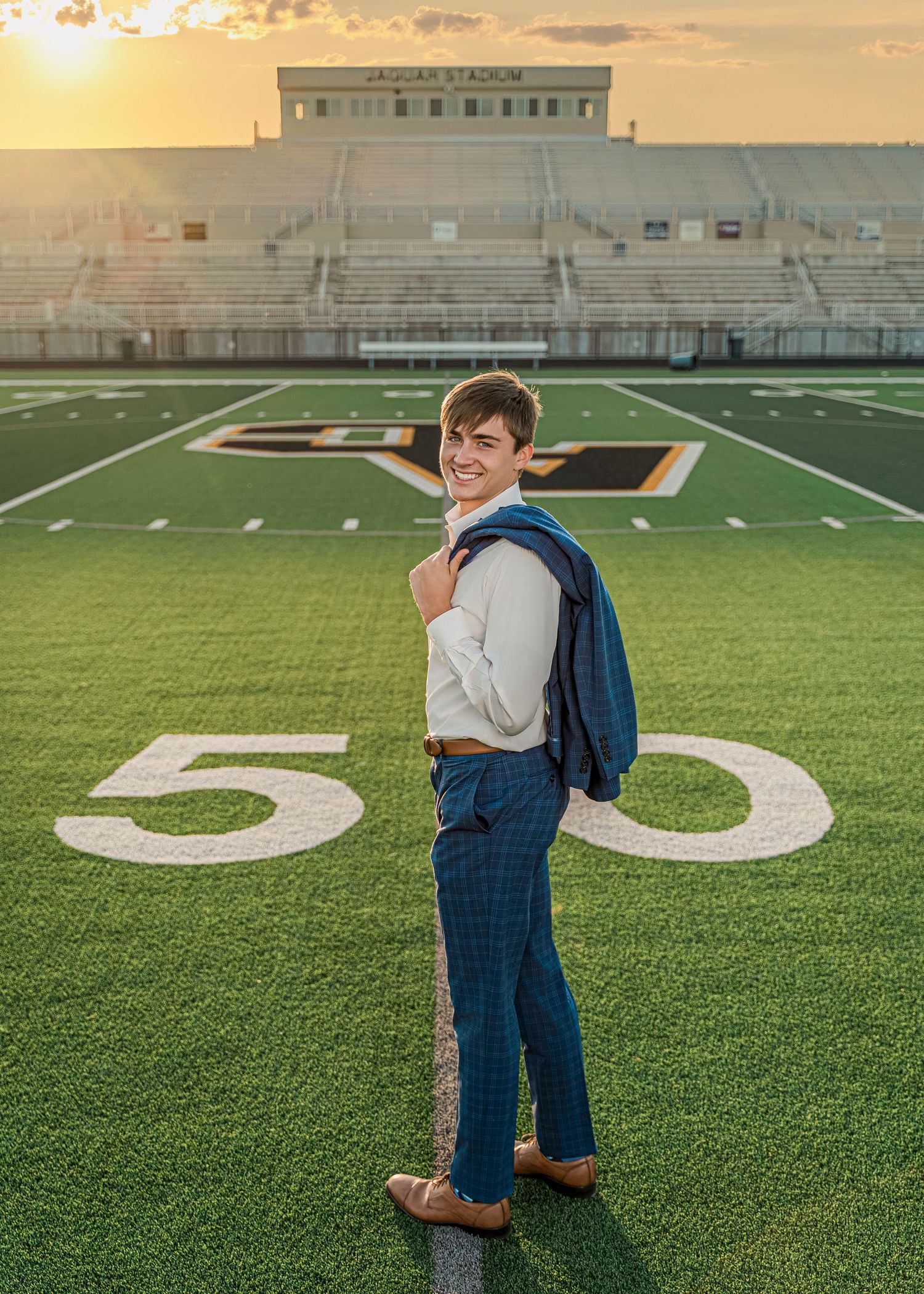 Senior portrait session on a football field during golden hour.