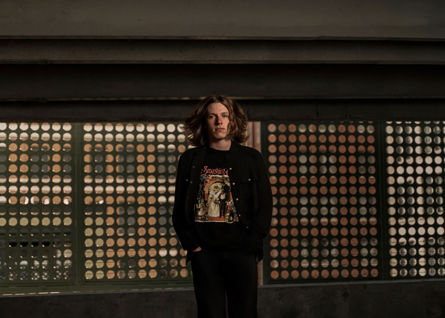 A dark and moody sequence of someone standing in front of a window with circular patterns casting dramatic shadows.