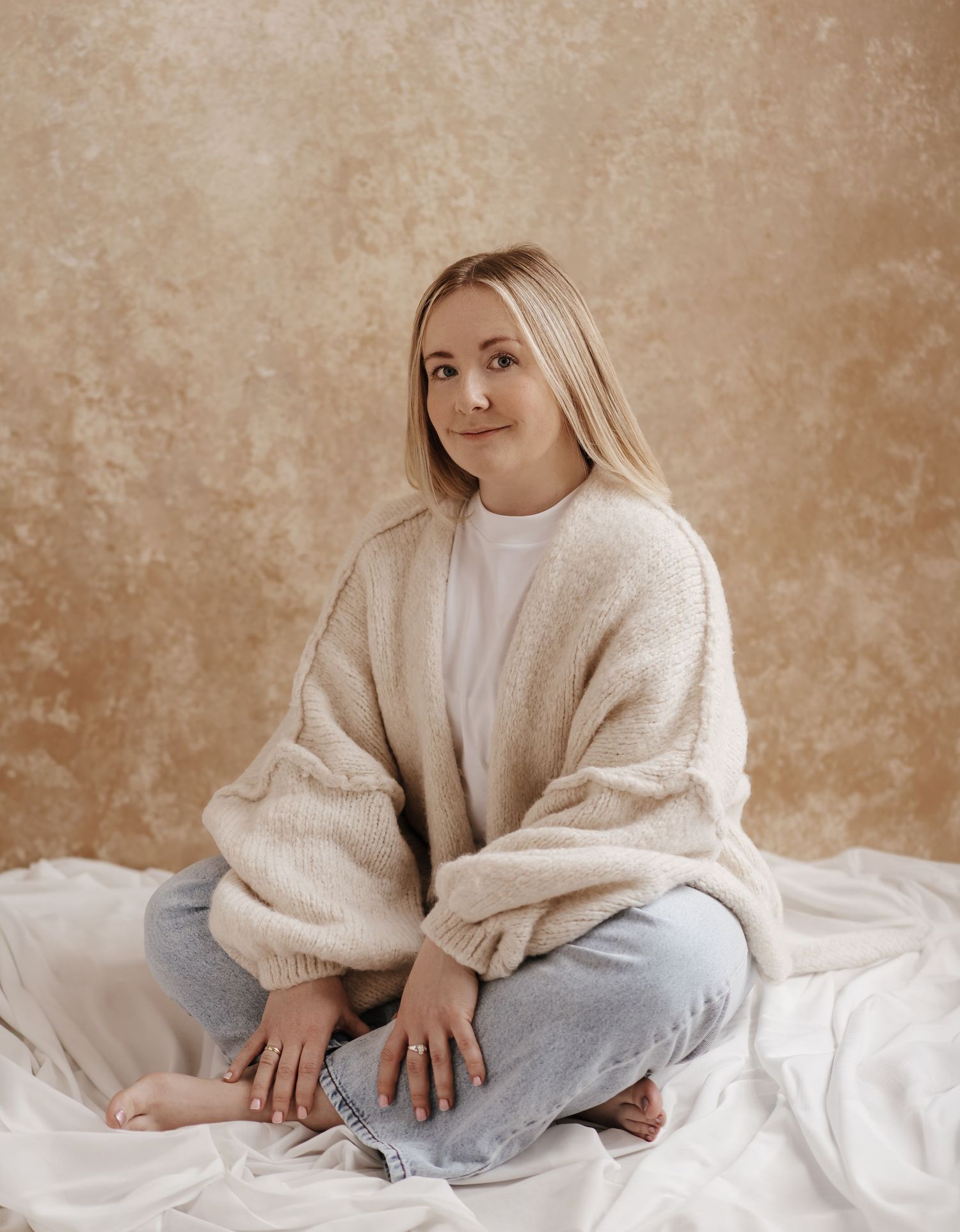 Artistic portrait series of a person in a white sweater and hat against a beige background.