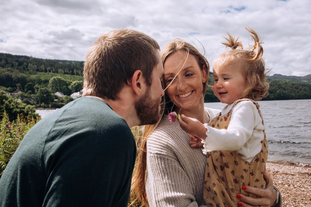 A happy family shares a joyful moment together by a scenic lakeside on a cloudy day.