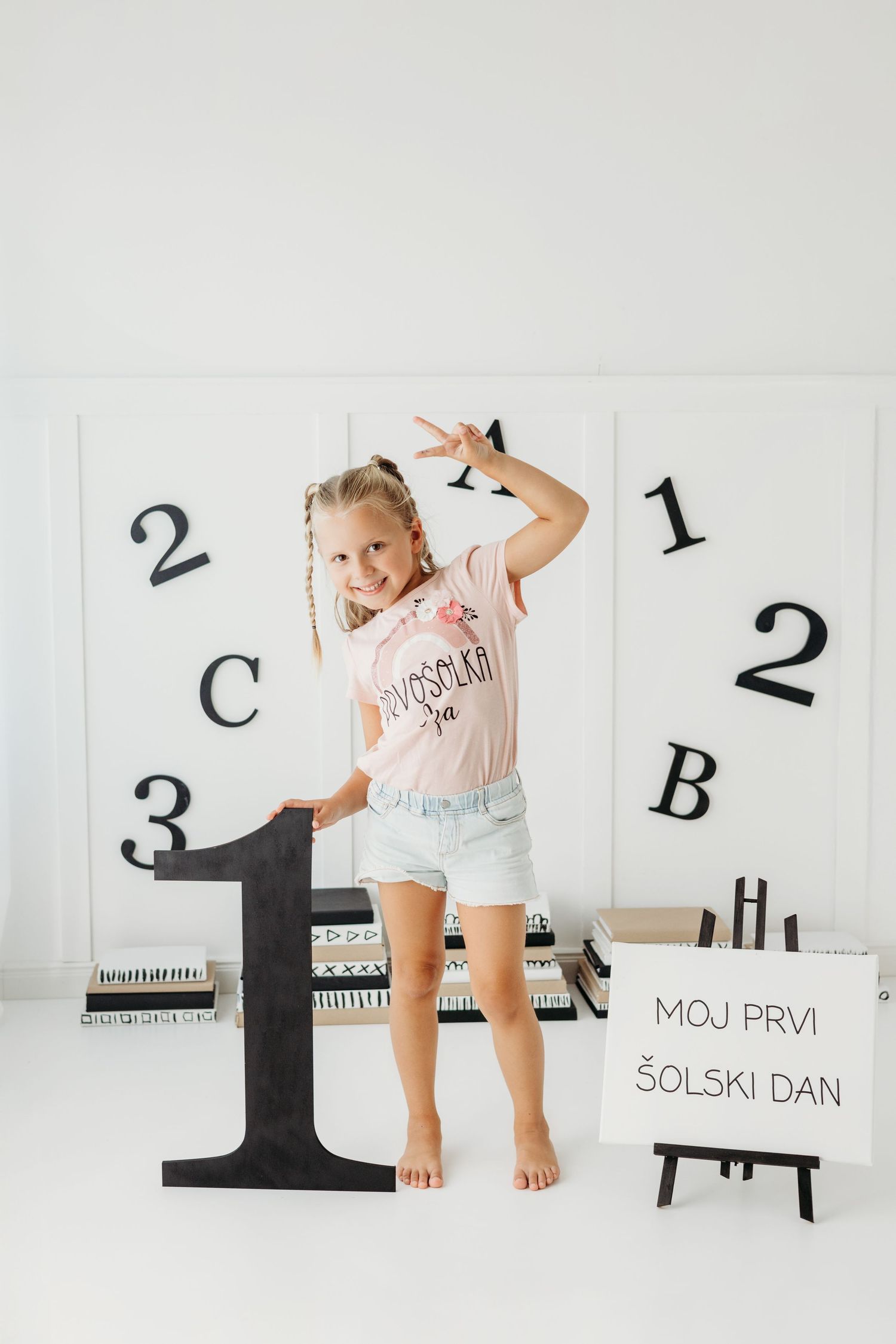 Young girl posing with number 1 sign and back-to-school decorations on her first school day.