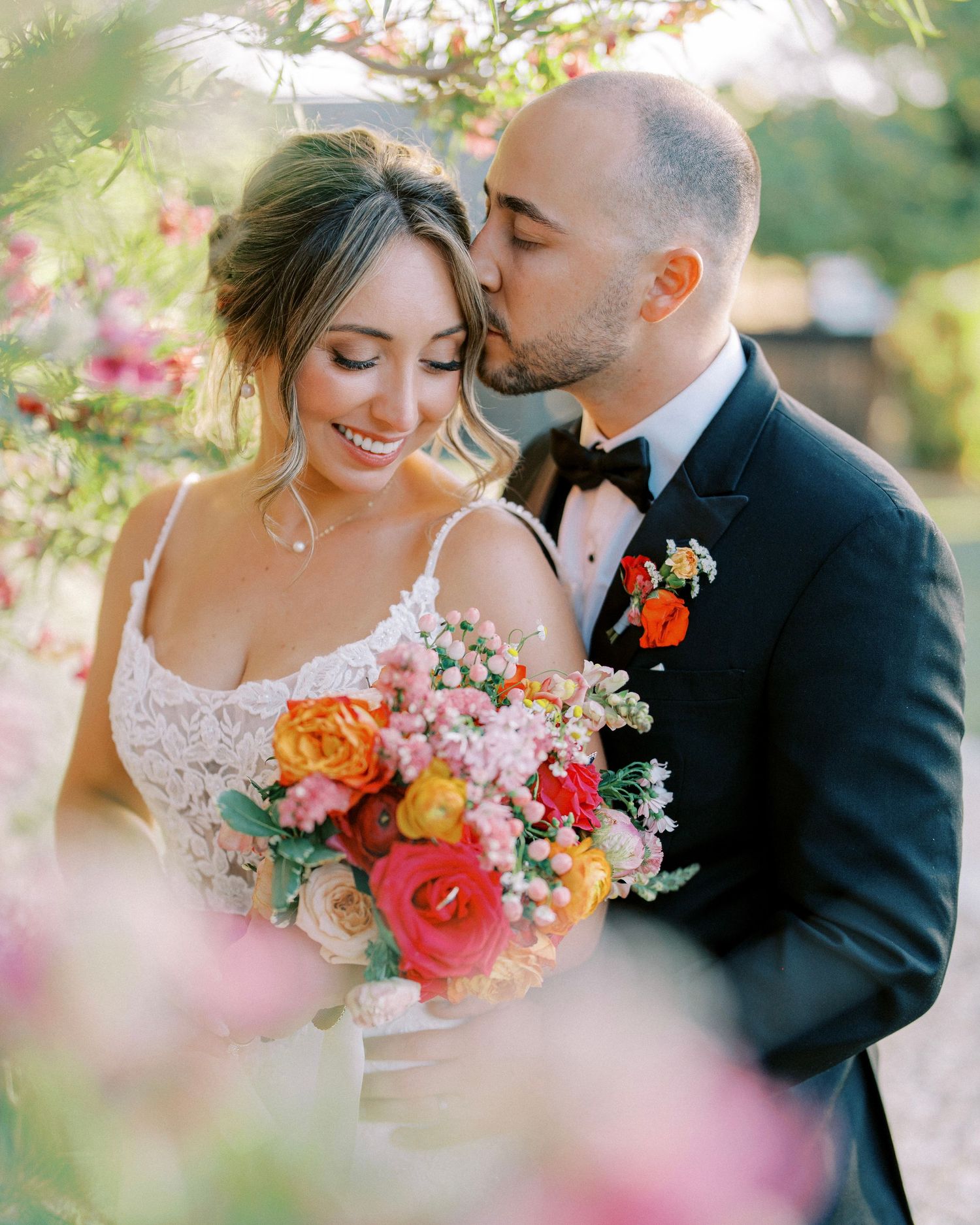 Pink bridesmaid dresses and white floral bouquets elegantly displayed in a row against a garden backdrop.