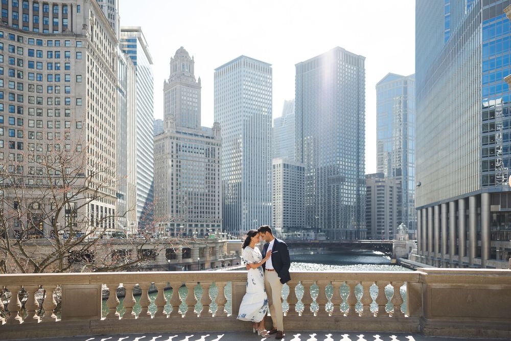 A couple shares a romantic moment on a balcony overlooking the Chicago River with iconic skyscrapers in the background.