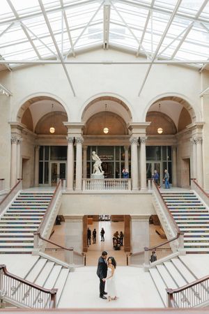 Grand white marble staircase with arched colonnades in an art museum interior creates symmetrical perspective.
