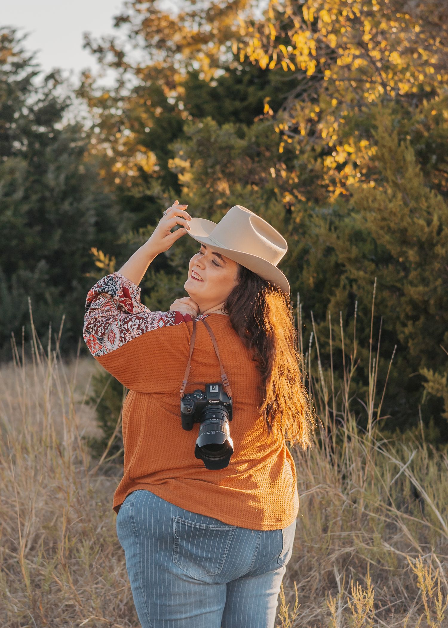 Person in burgundy dress twirling in golden sunlit field with sunflowers.