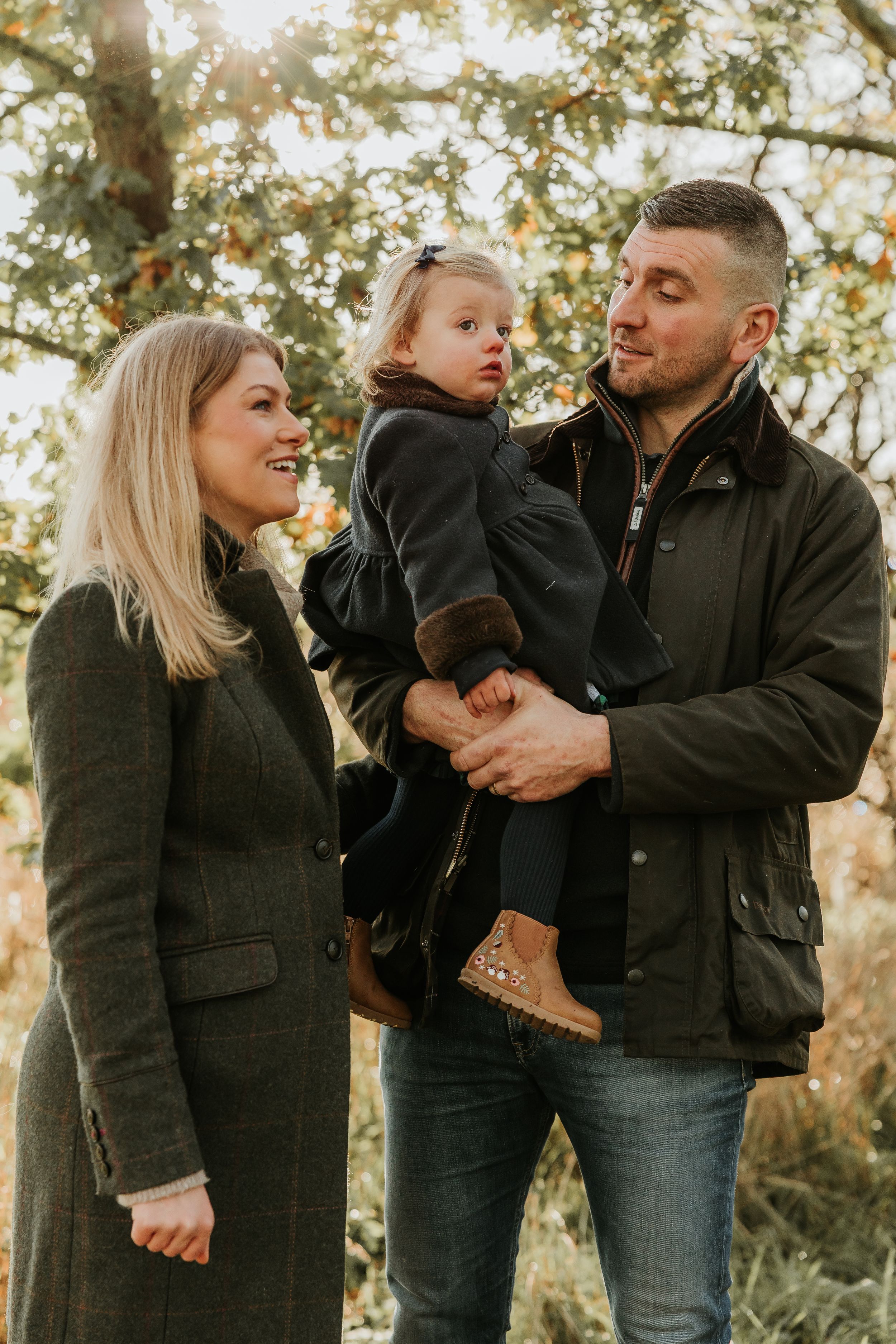 A family shares joyful moments together outdoors during a golden hour photo session in nature.