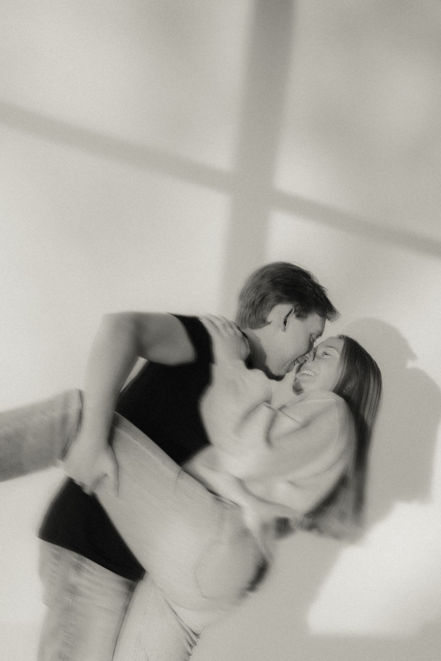 black and white motion blur portrait of couple kissing in window lighting.