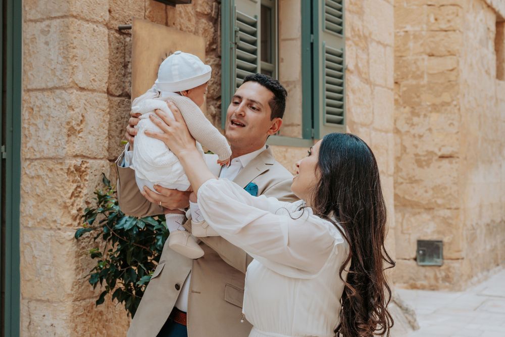 Couple dancing and embracing in front of traditional Mediterranean architecture.