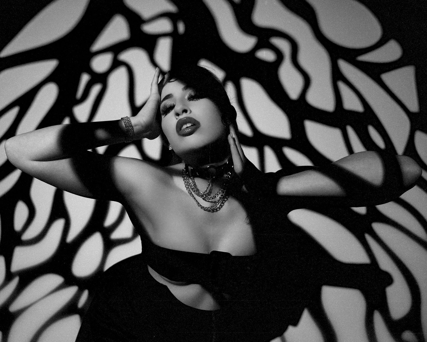 Dramatic black and white portrait with abstract shadow patterns.