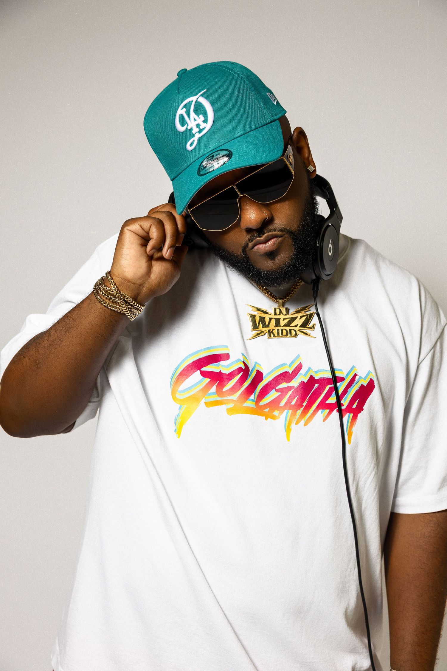 A series of four connected photos showing someone wearing a white t-shirt and teal baseball cap against a light background.