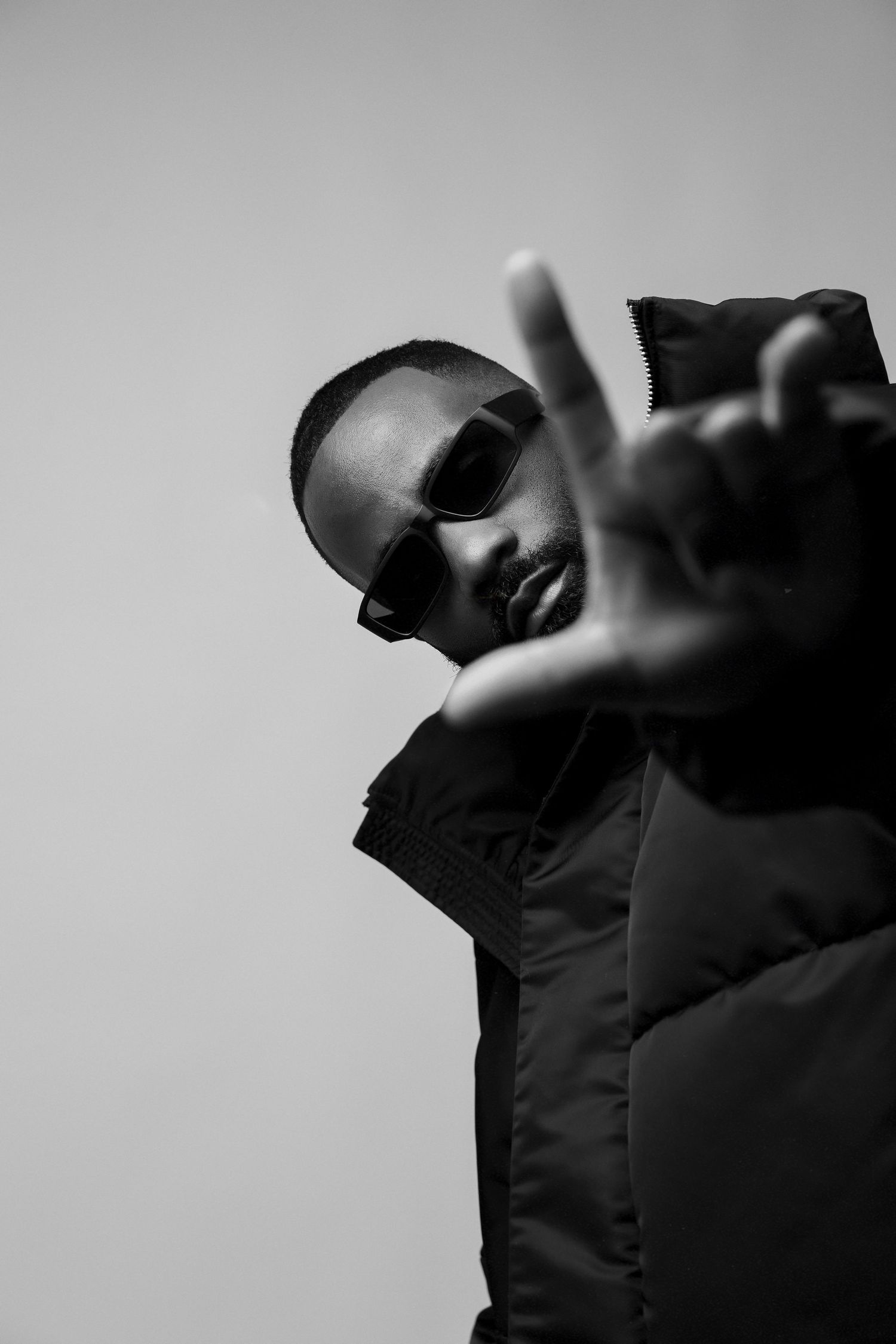 Black and white portrait in sunglasses making peace sign gesture.