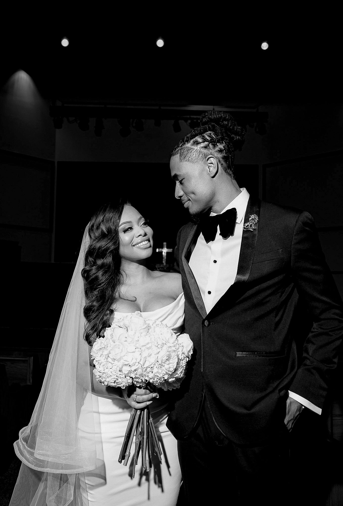 Black and white candid wedding moment capturing tender exchange between newlyweds.