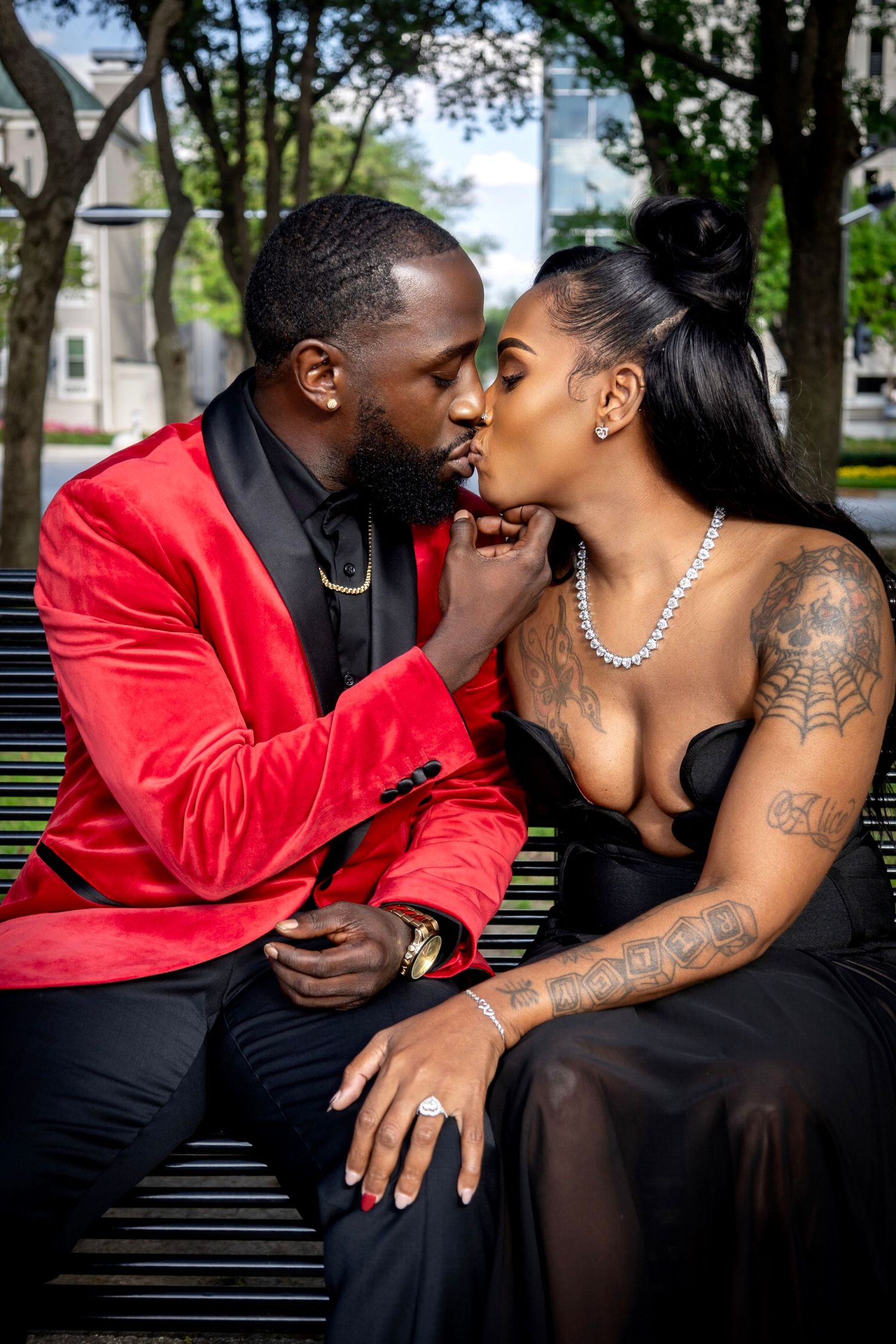 Romantic couple in formal attire sharing an intimate moment on a park bench.
